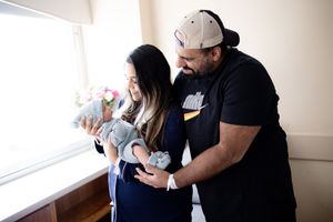 Couple admiring their newborn baby by a window in a hospital room, sharing a tender family moment at Fort Sanders Medical Center.