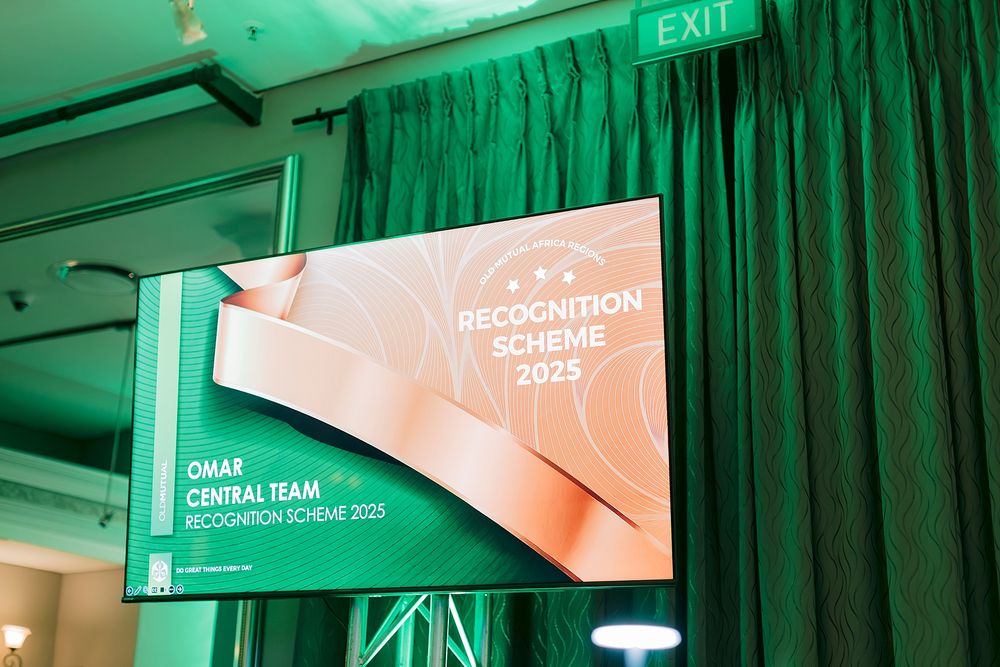 OMAR Central Team Recognition Scheme 2025 displayed on a large screen at a formal event venue with green curtains.