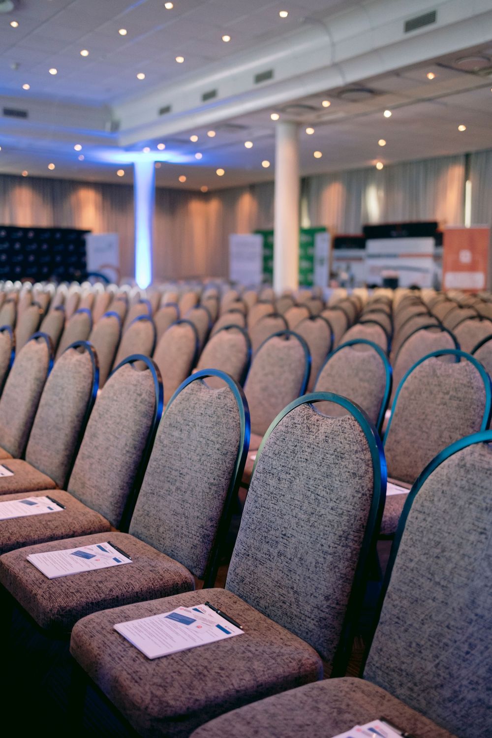 Rows of empty chairs with documents placed on seats in a conference hall ready for a corporate event.