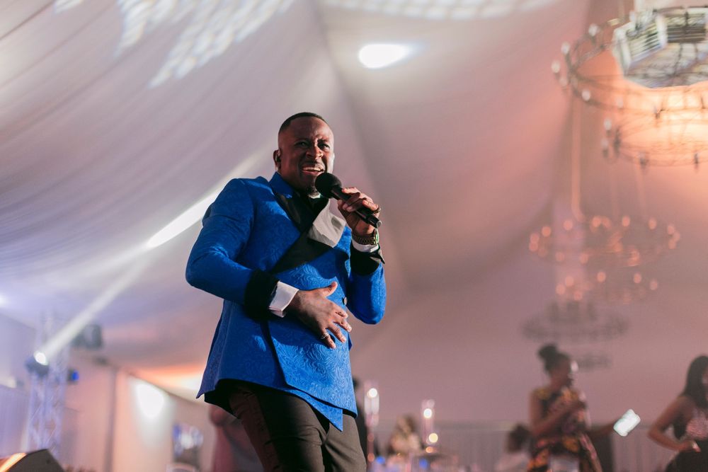 Man in blue blazer performing on stage at an elegant event venue.