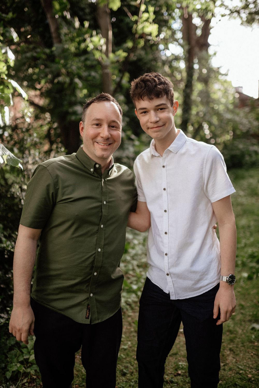 Two siblings in contrasting white and green shirts share playful moments outdoors.