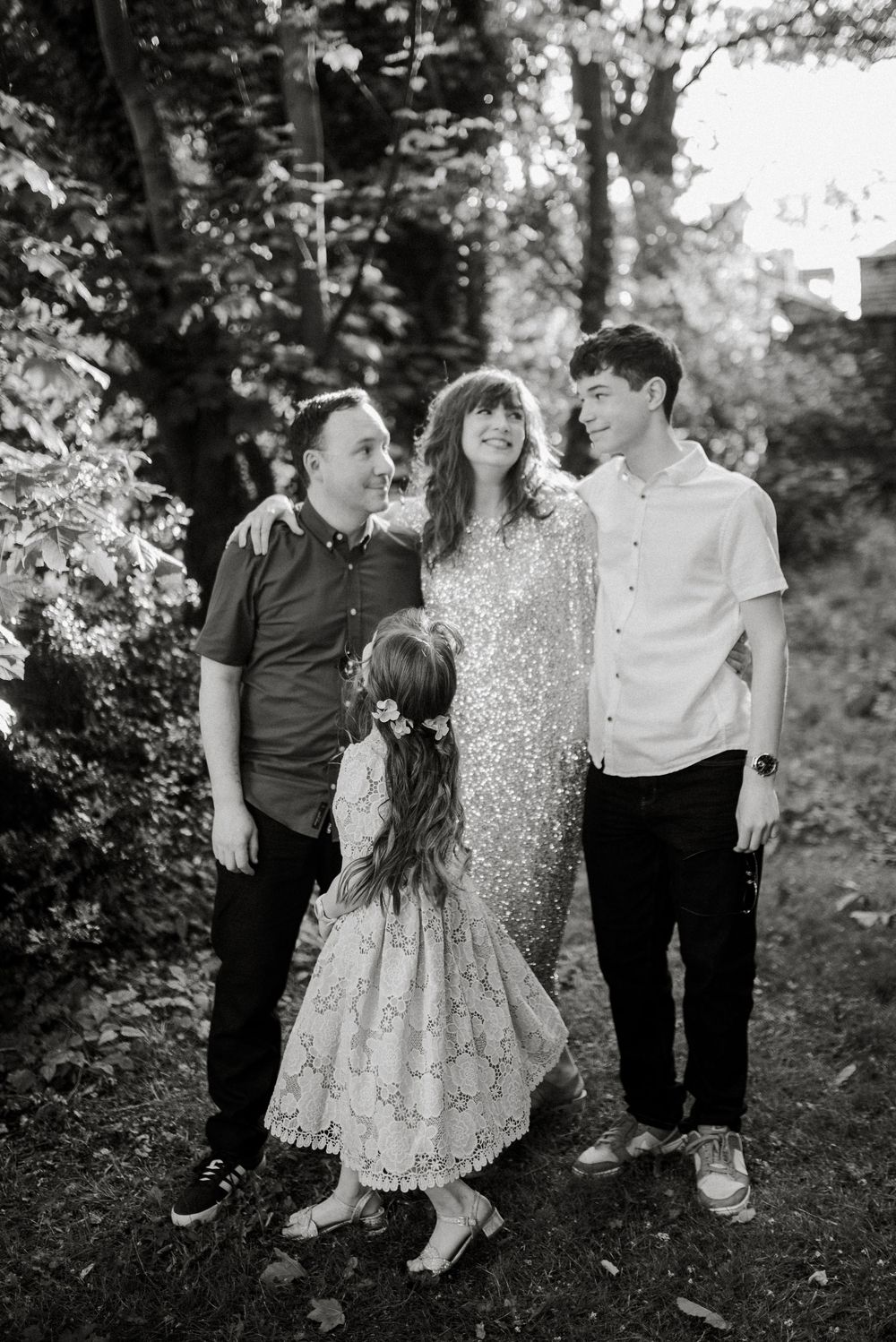 Family group in casual attire posing together in a wooded outdoor setting.