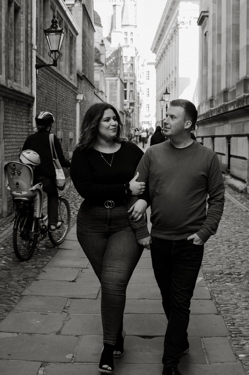 Couple walking together down a cobblestone street in black and white.