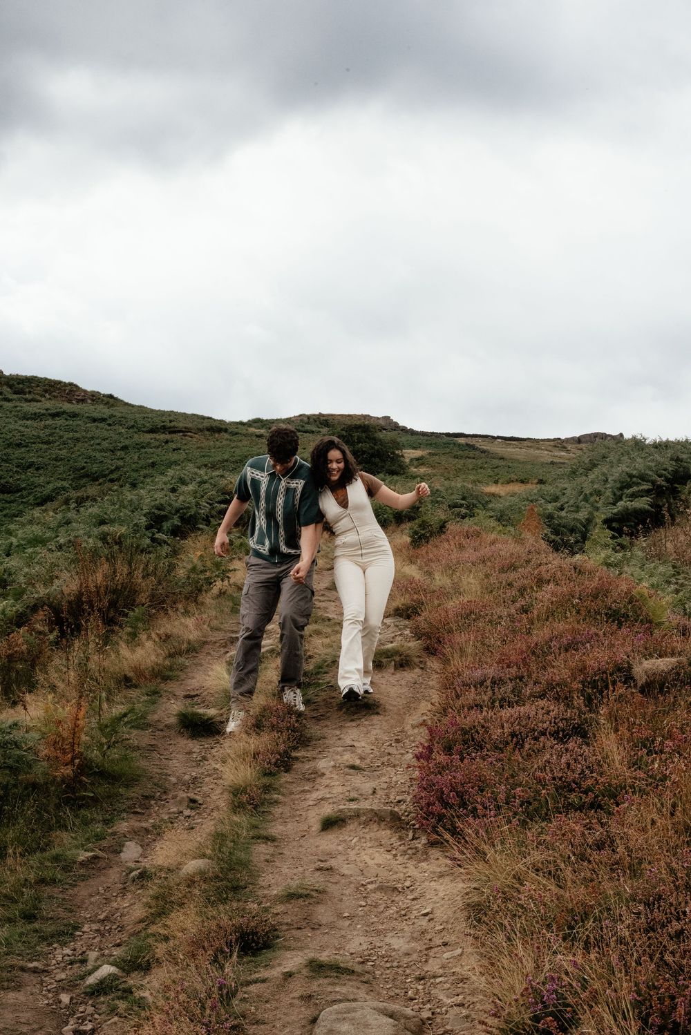 Couple walking and laughing together on a scenic mountain trail.