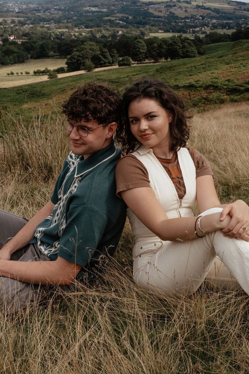 Couple relaxing together in rolling countryside hills during golden hour.
