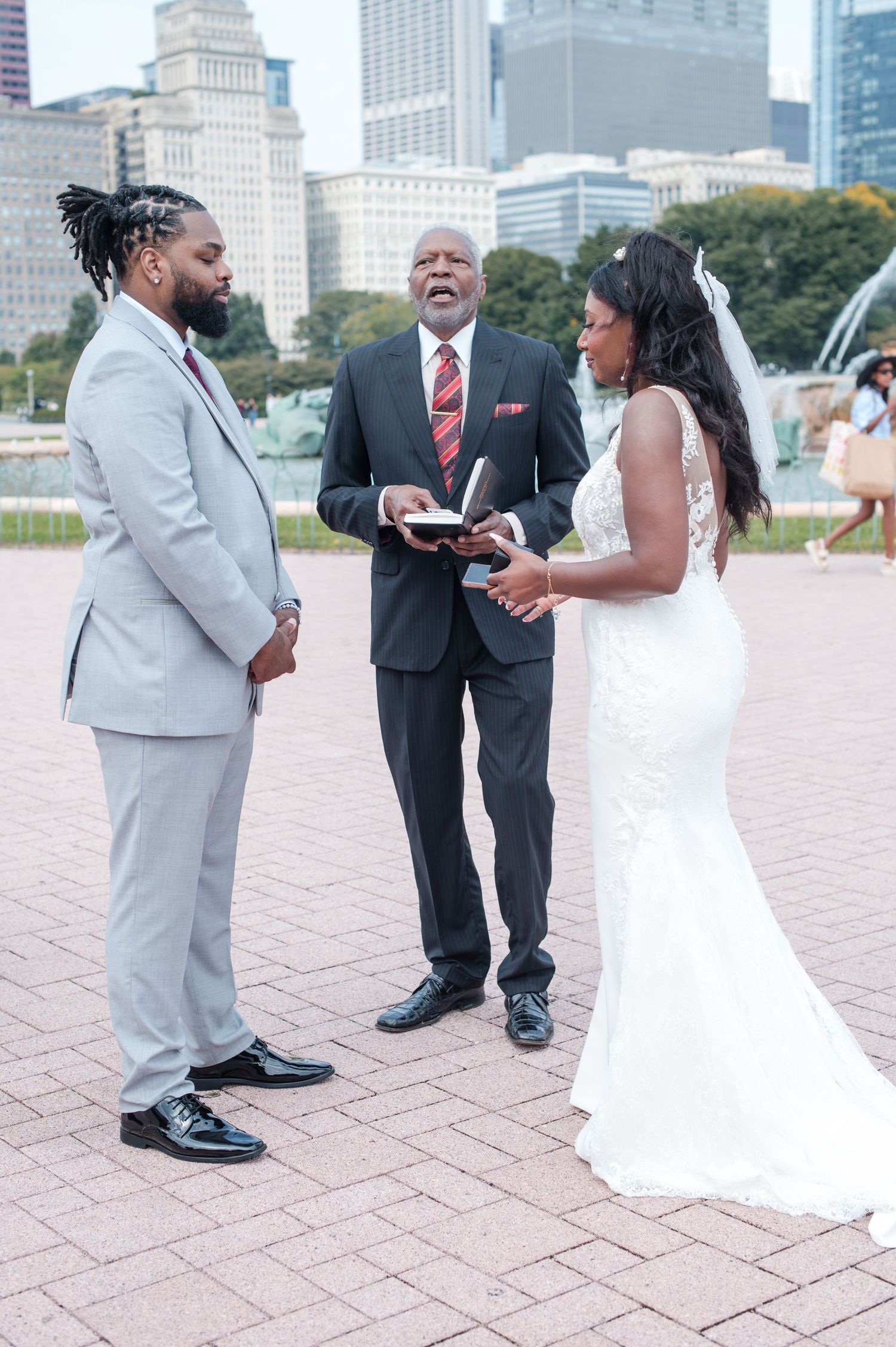 Bride and groom exchange vows with officiant at outdoor Chicago wedding ceremony near Buckingham Fountain.