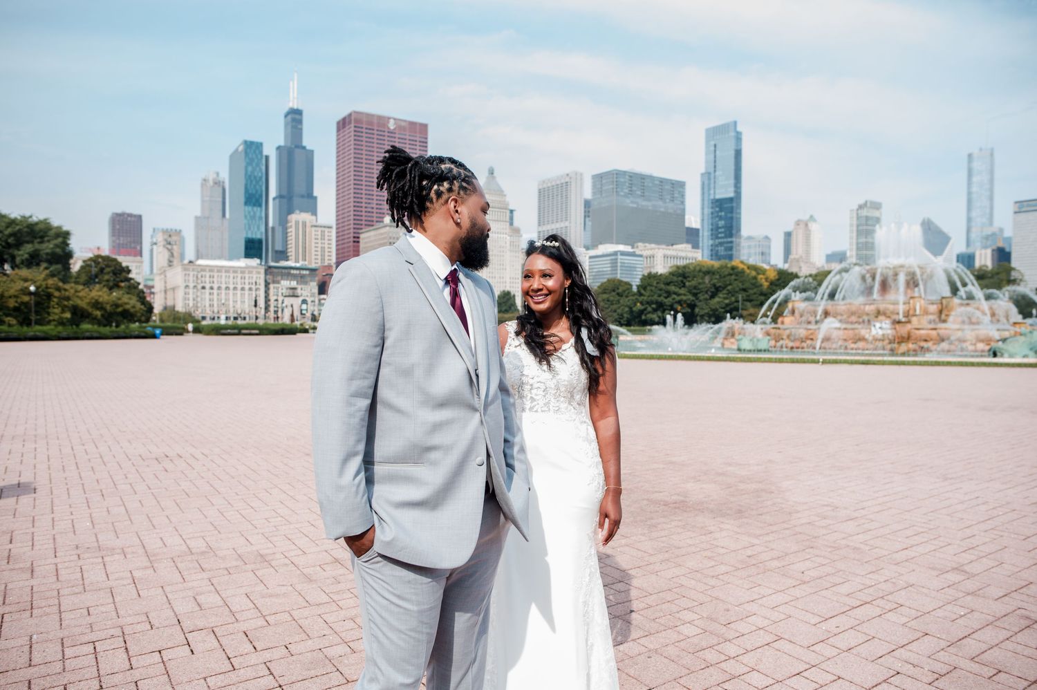 A bride and groom share a romantic moment in front of Buckingham Fountain with the Chicago skyline backdrop.