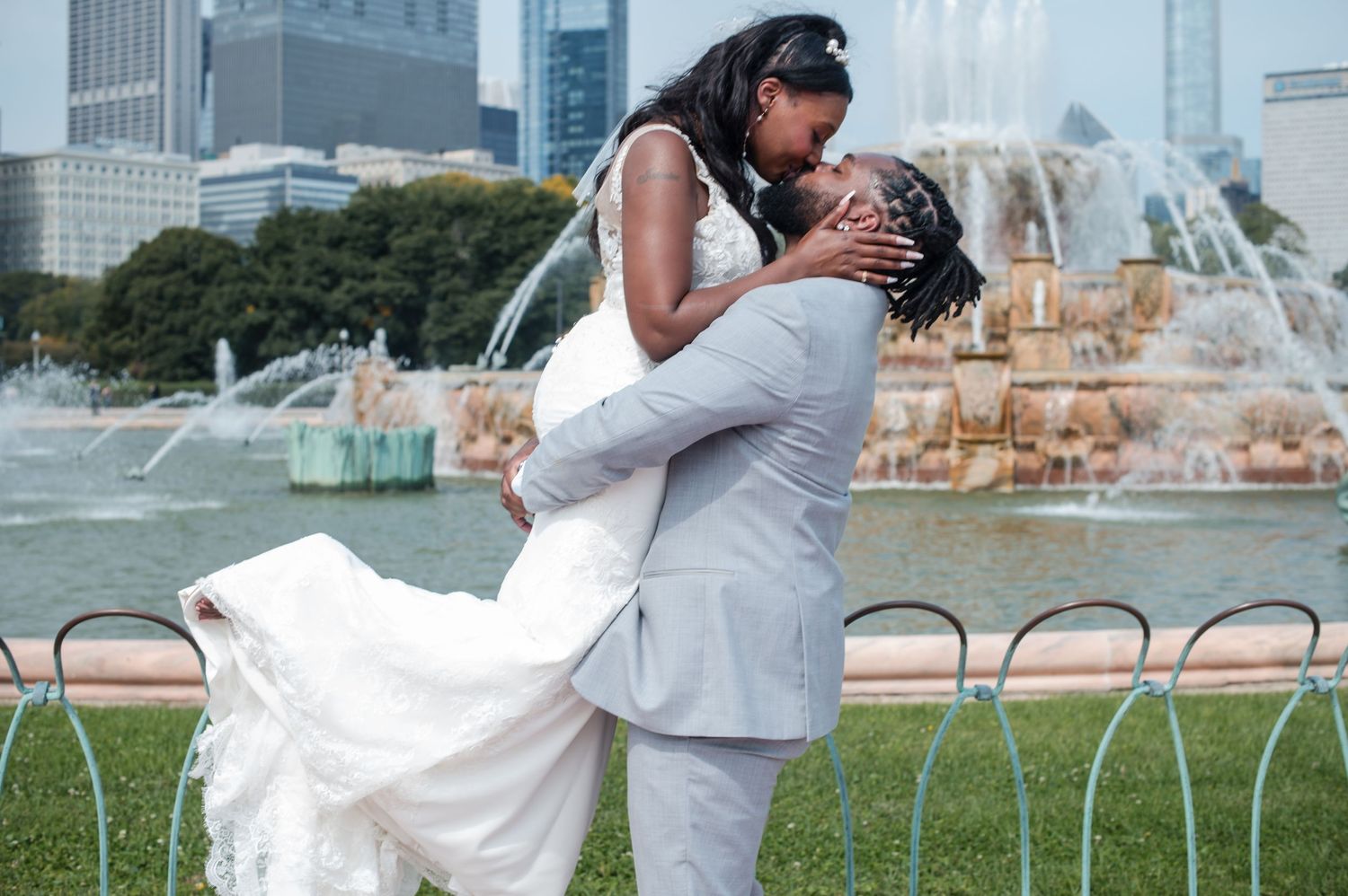 Newlywed couple sharing a romantic dip kiss in front of Buckingham Fountain in Chicago on their wedding day.