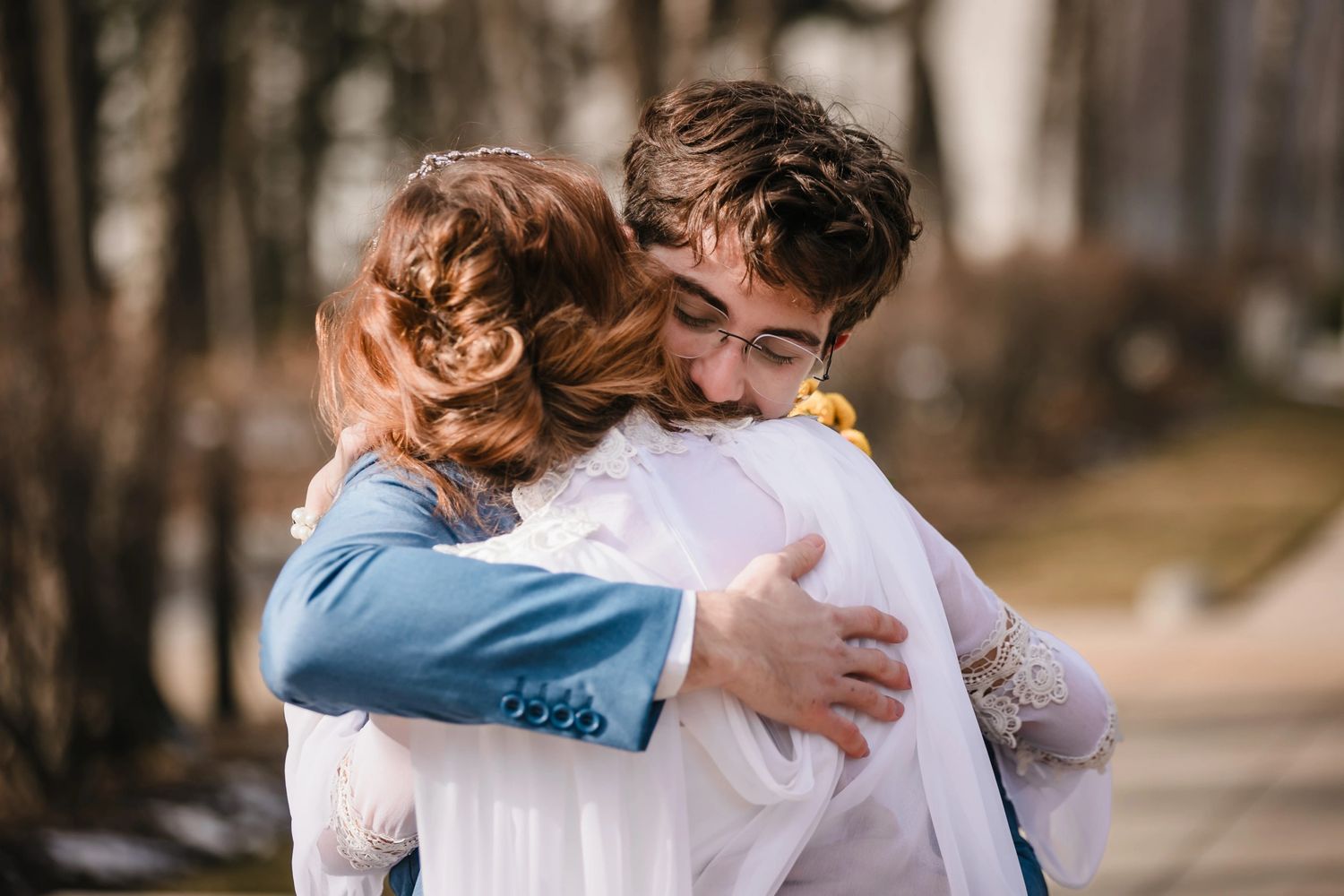 The bride and groom hug each other passionately after completing their first look on their wedding day. The groom's joyous face is visible.