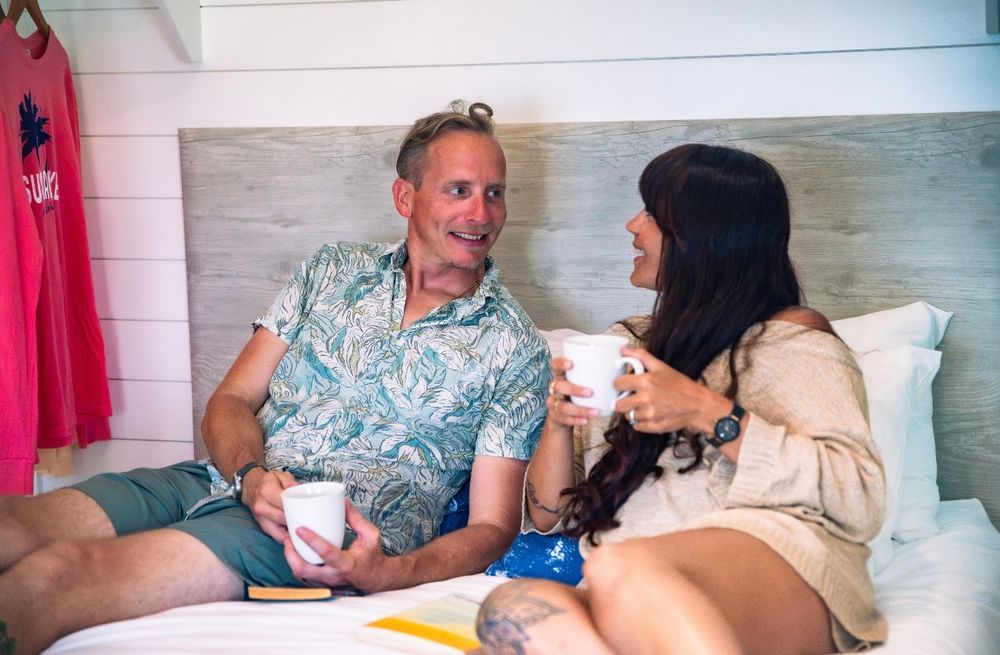 Smiling couple enjoying morning coffee together in a bright cottage bedroom at Sugarloaf Key Resort.