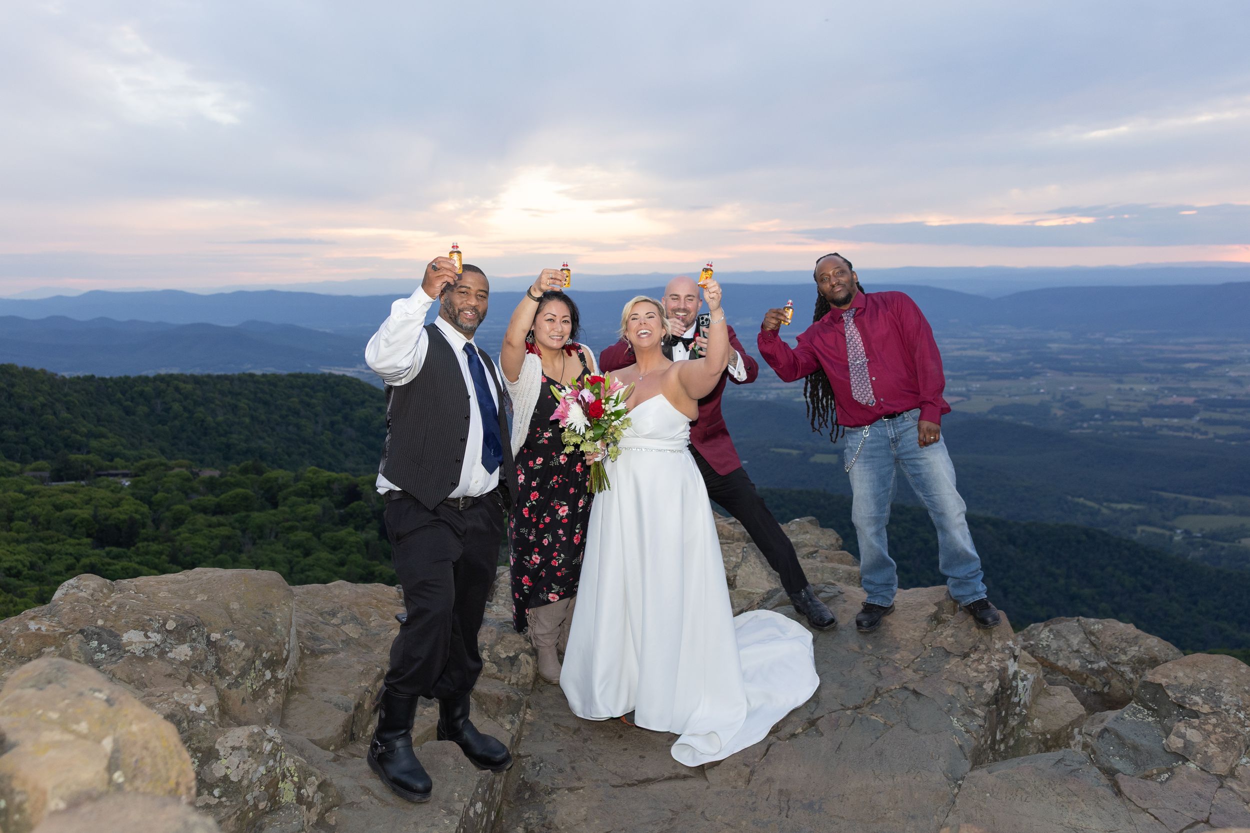 Wedding party celebrating on a mountain overlook at sunset with panoramic valley views.