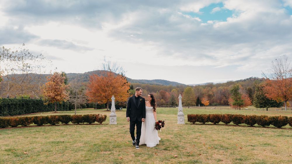Bride and groom standing in a manicured garden with autumn foliage and mountain views on their wedding day.