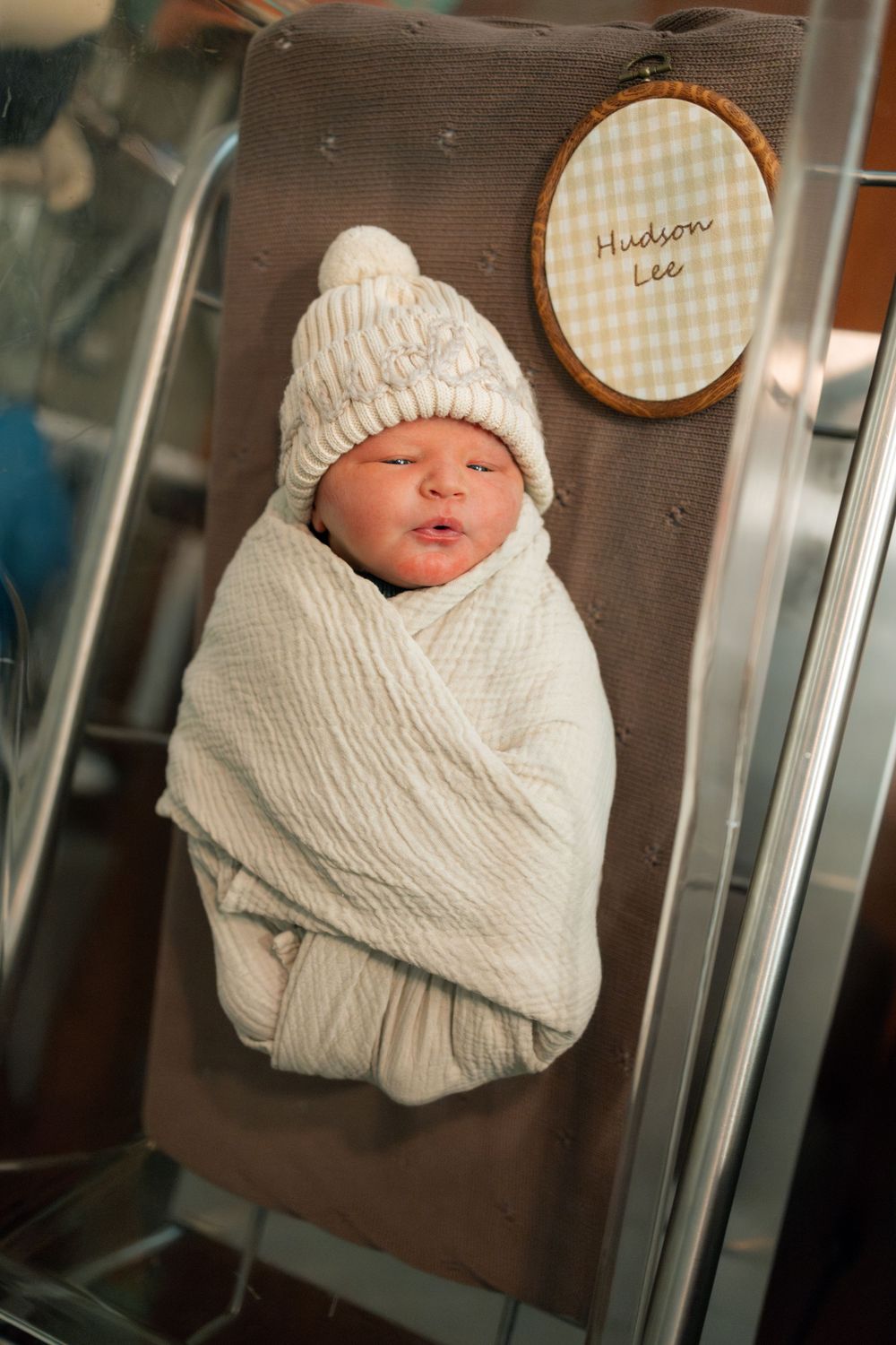 Newborn baby Hudson Lee swaddled in white knit blanket and hat, resting in hospital bassinet during a Fresh 48 session at Parkwest.