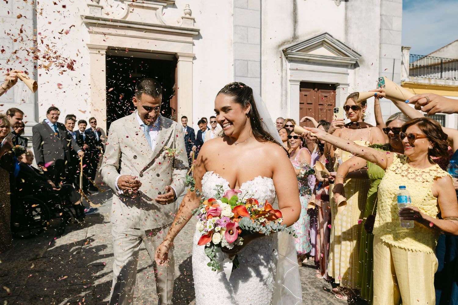 a noiva e o noivo saem da igreja da sé de Beja debaixo de uma chuva de confettis num dia de muito sol