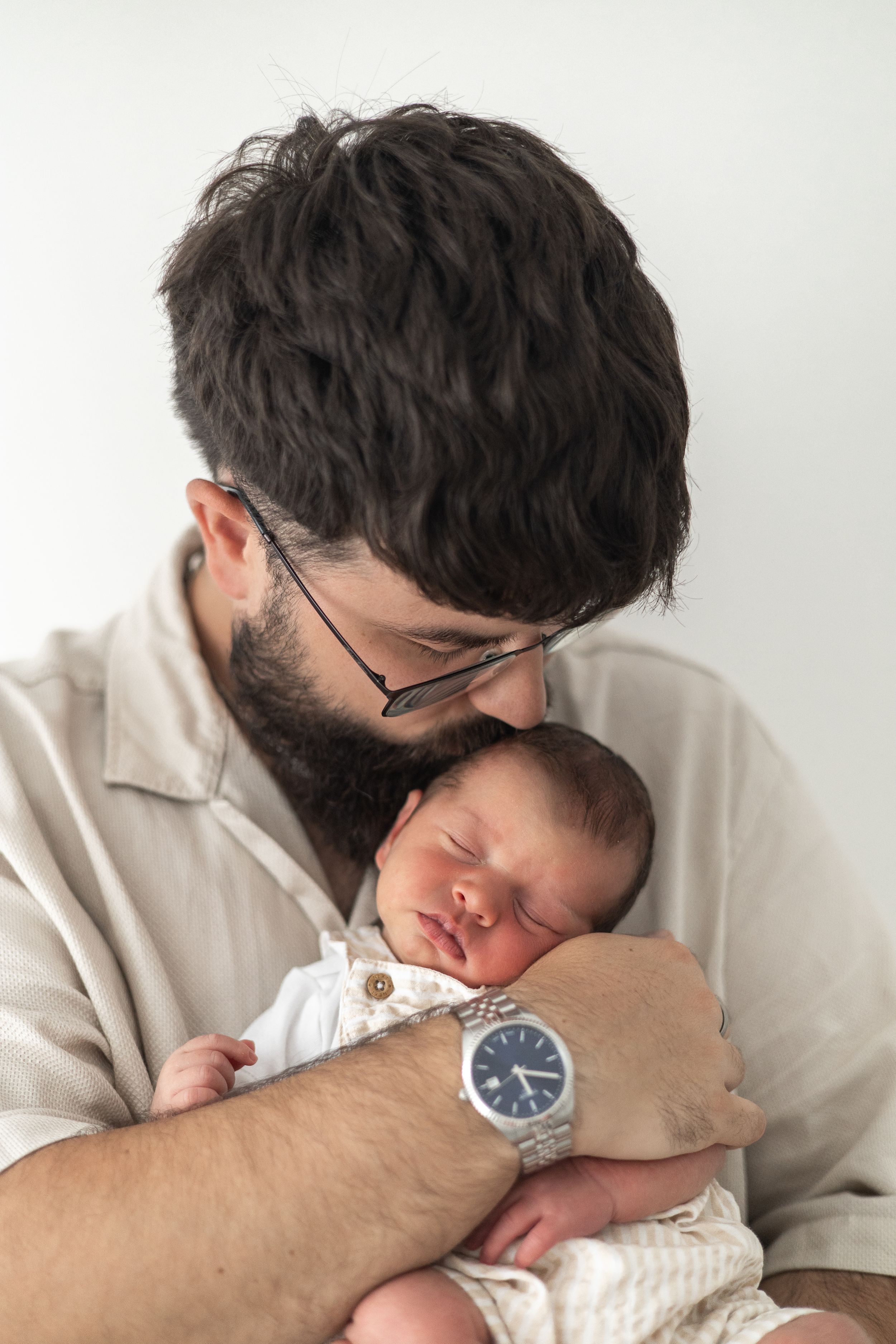 Dad tenderly kisses sleeping newborn baby cradled in his arms, Newborn photographer Nottingham