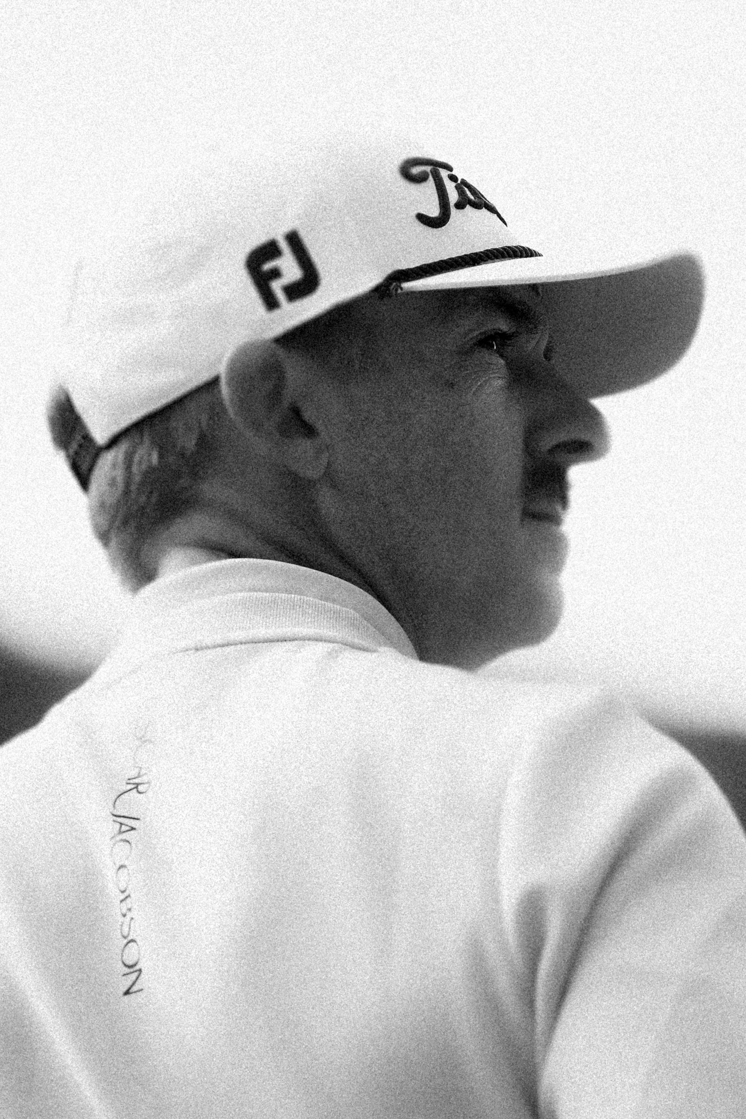 Black and white profile portrait of a golfer wearing an FJ cap and Titleist gear outdoors.