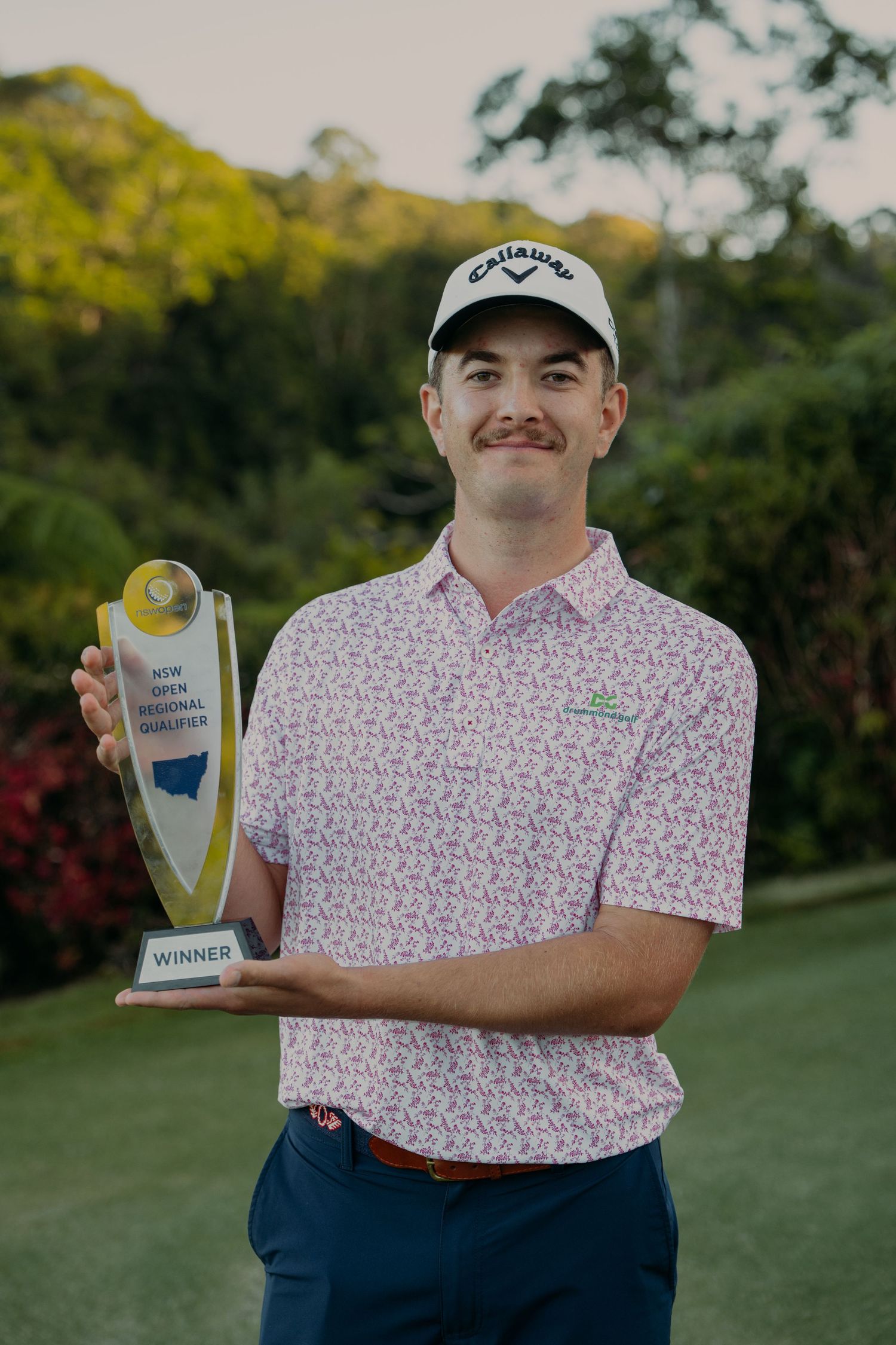 Young golfer proudly holds a Winner trophy at the NSW Inter Regional Qualifier golf tournament, wearing a Callaway cap.