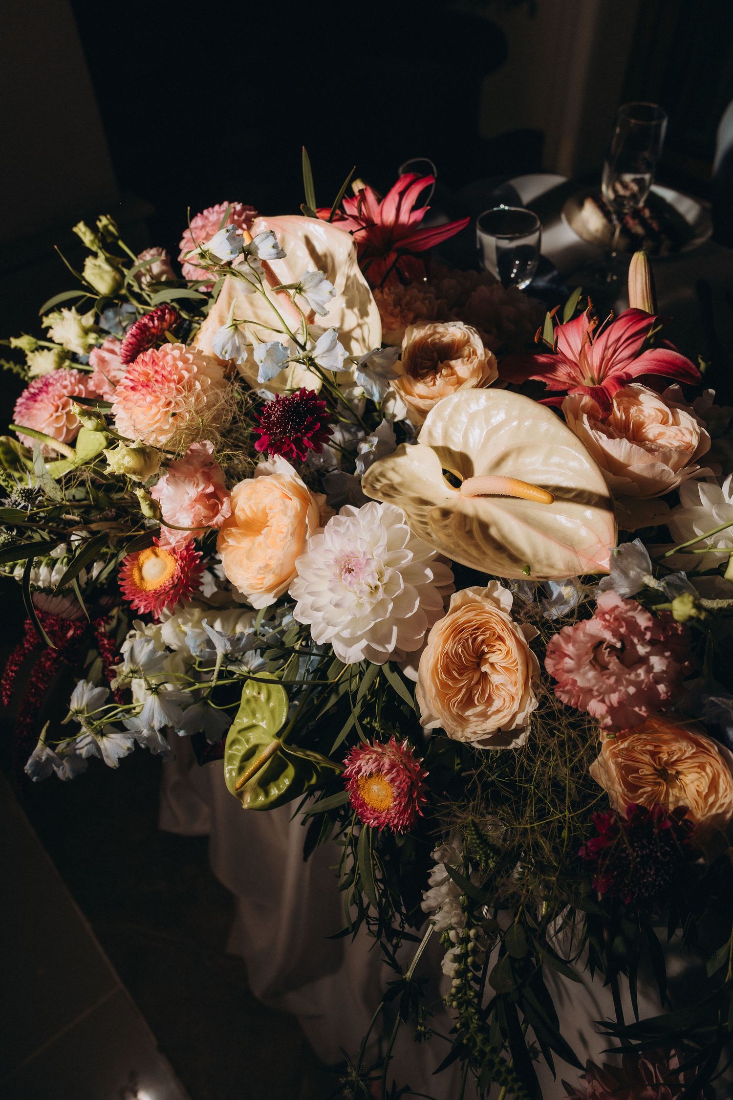 Lush floral arrangement featuring roses, dahlias, anthuriums, and mixed blooms in pink, peach, and white tones.