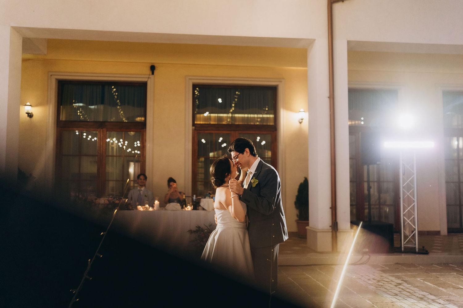 Bride and groom share their first dance in an elegantly lit wedding reception venue with warm ambient lighting.