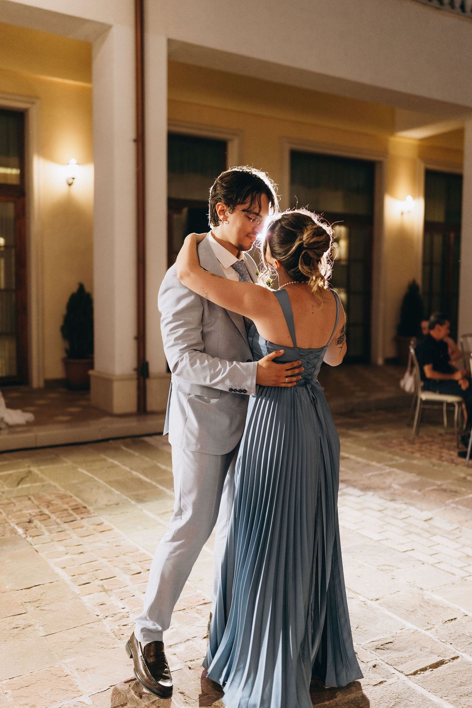 Couple sharing a romantic dance at an elegant evening wedding reception in a warmly lit venue.
