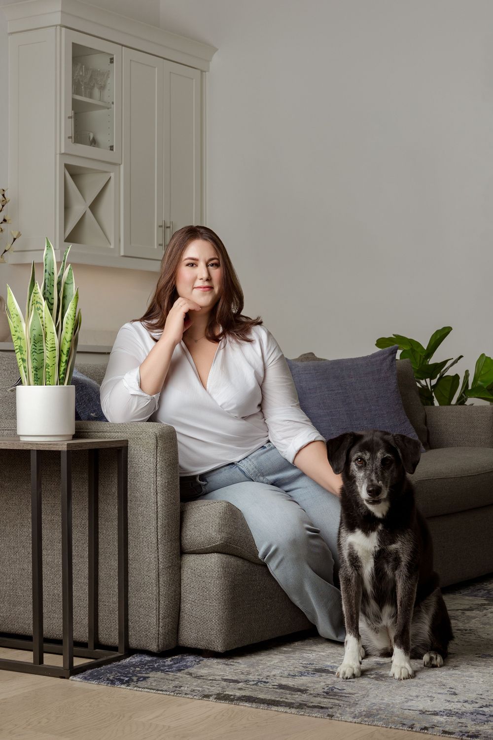 Miami personal branding portrait of a woman in a white blouse seated at home beside her black-and-white dog.