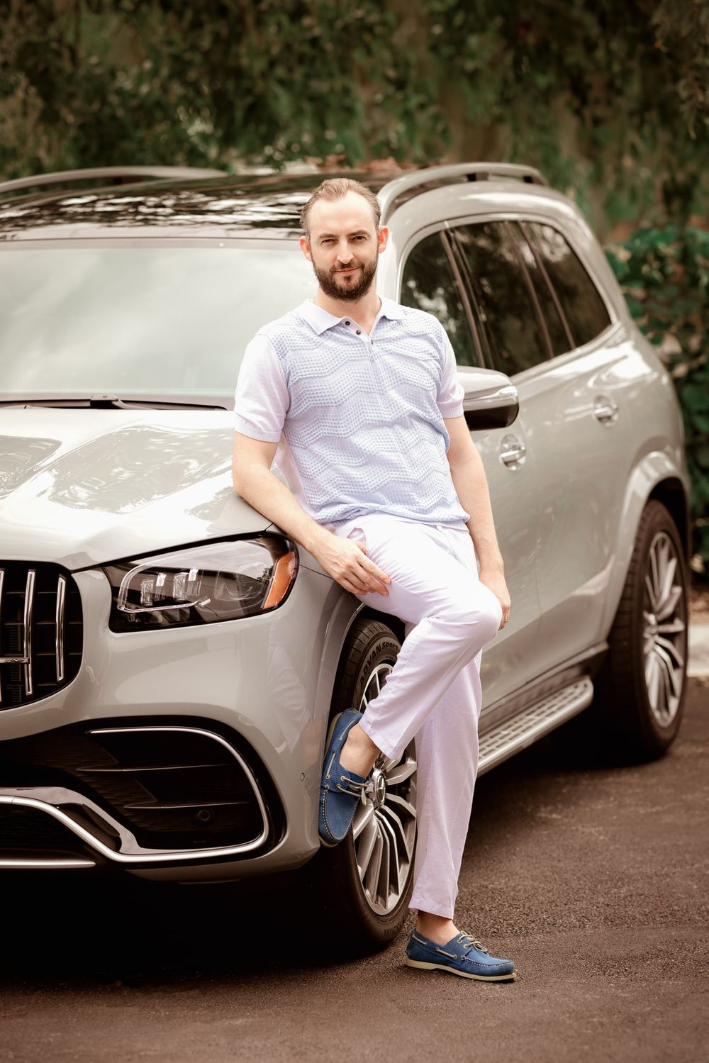 Miami personal branding portrait of a man leaning against a luxury SUV outdoors.