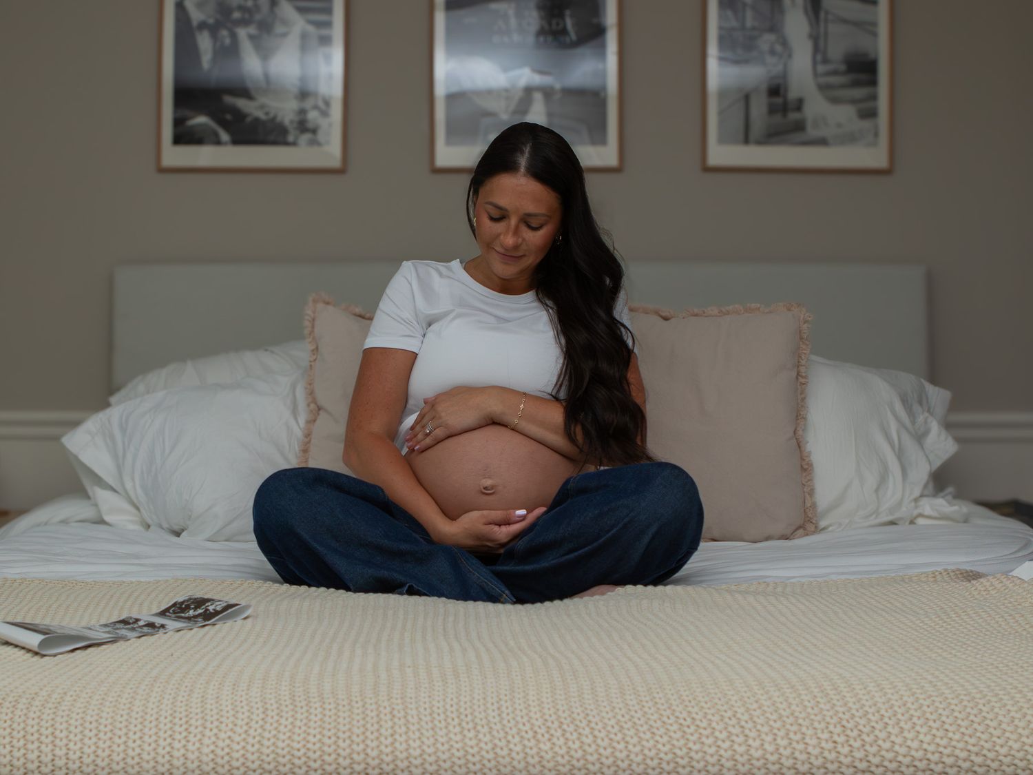 Pregnant mom smiling at her pregnant belly in her bed in Strongsville.