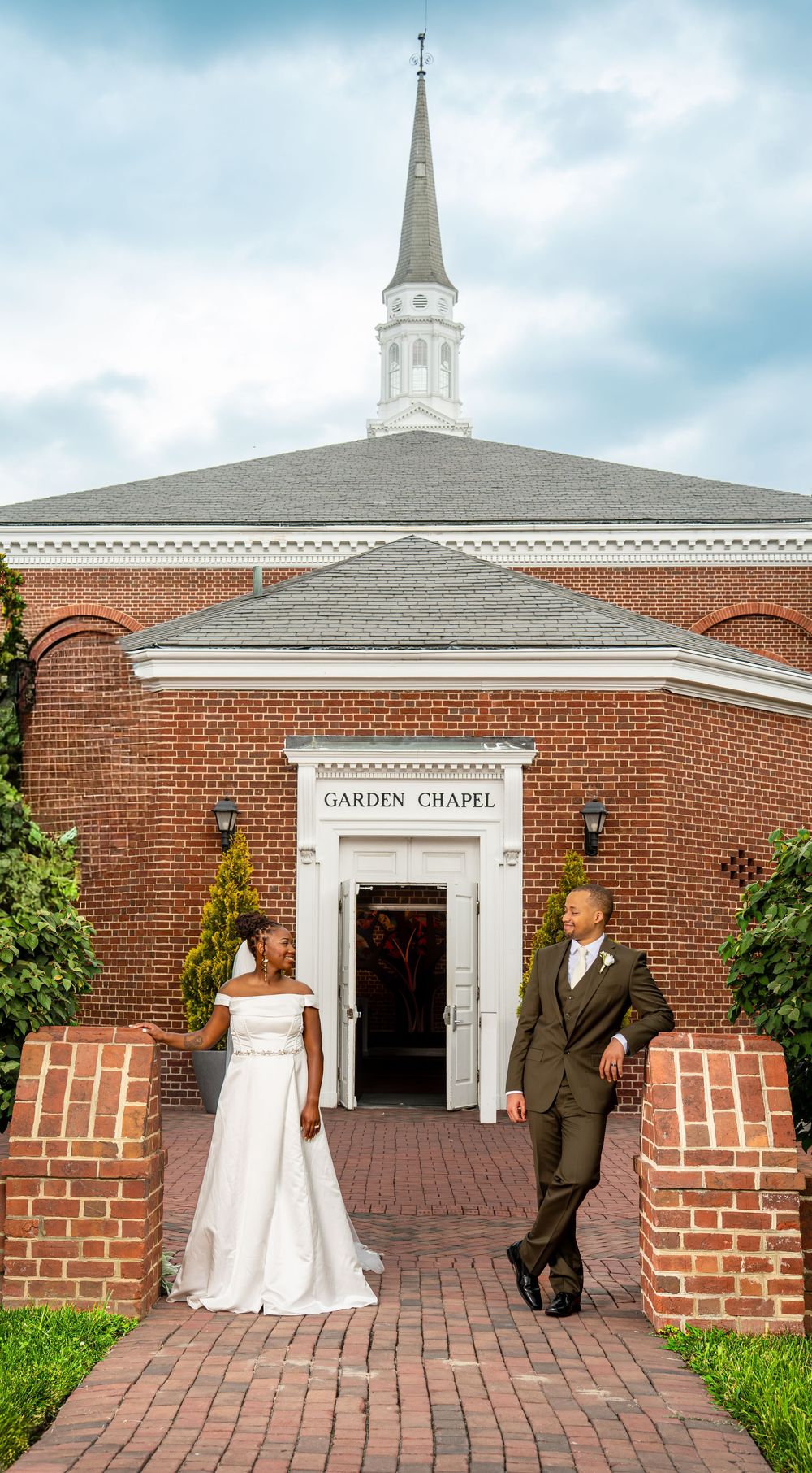 Bride and groom standing at entrance of brick Garden Chapel on wedding day.
