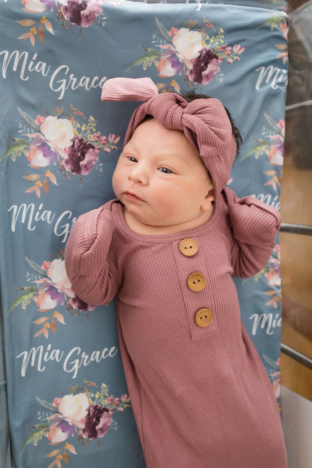 Newborn baby girl named Mia Grace in pink ribbed gown with bow headband on floral personalized blanket.