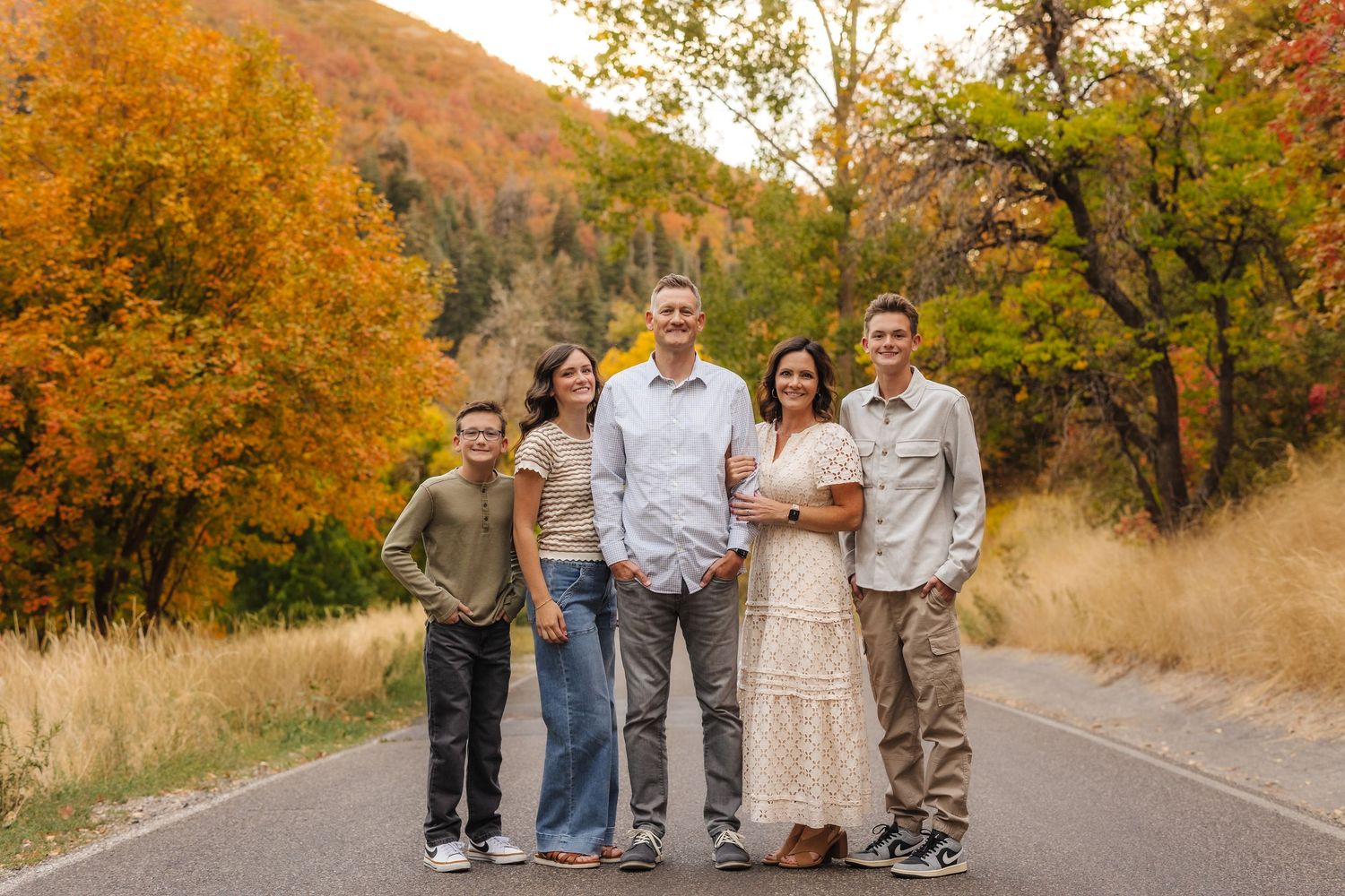 Utah Family Photographer in Utah photgrapher, Family in neutral tones smiling at camera in a fall foliage scene