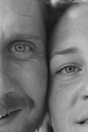 Black and white close-up portrait of a man and woman's faces side by side, showing expressive eyes and features.