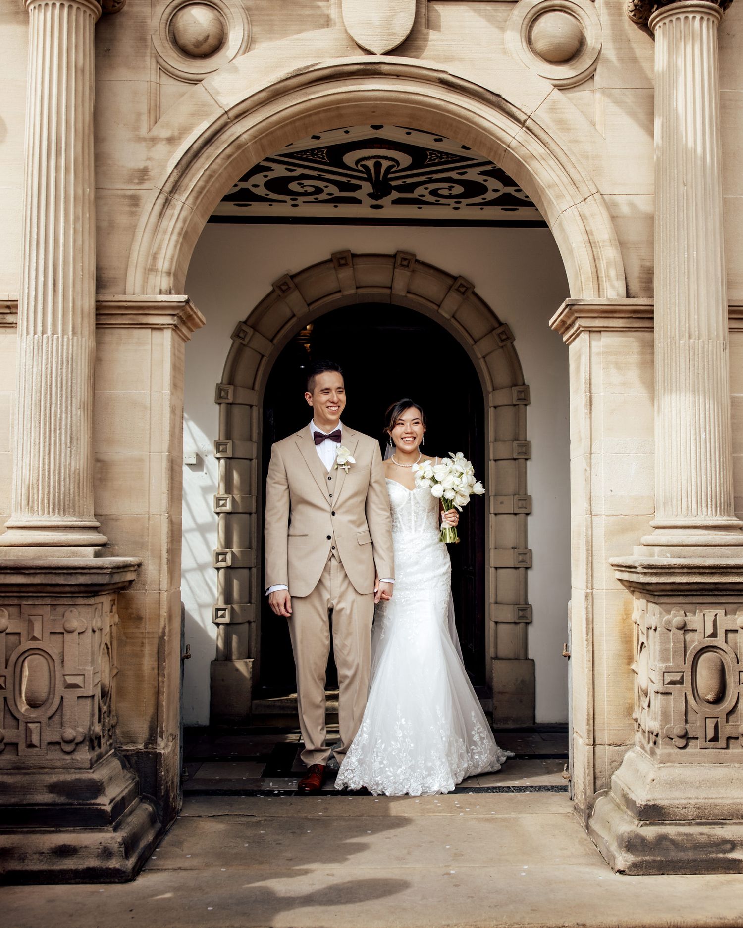 Bride and groom pose between two iconic red British telephone boxes on their wedding day.