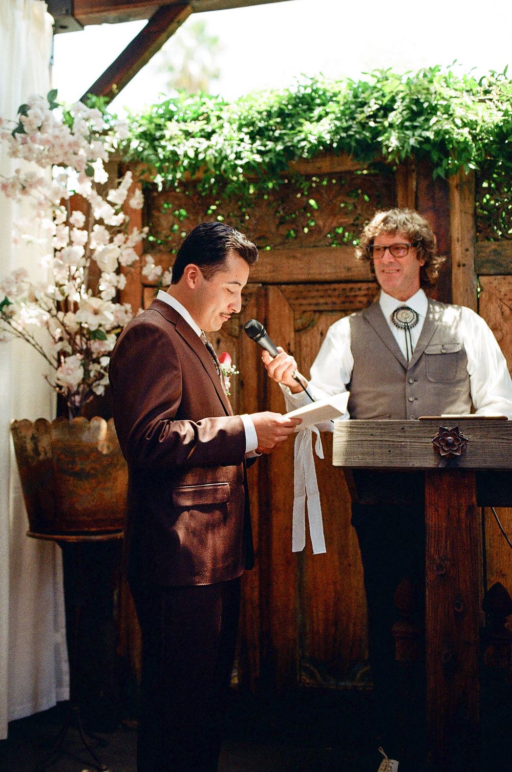 groom reads vow book in film wedding photography image