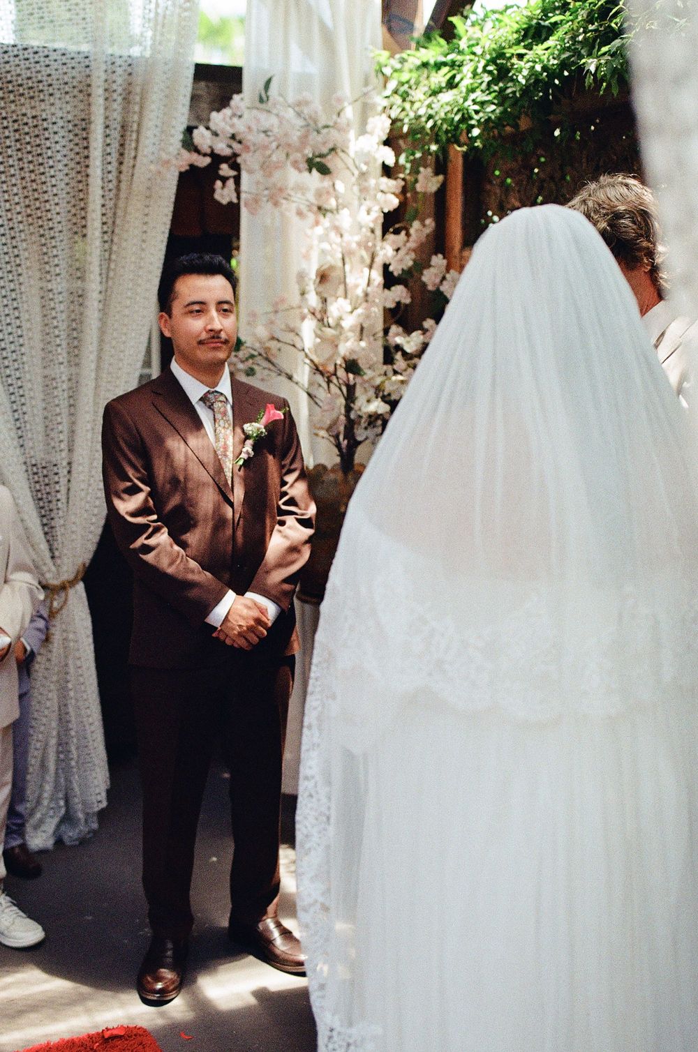groom standing at altar of old brown house sharing vows with bride, film wedding photography