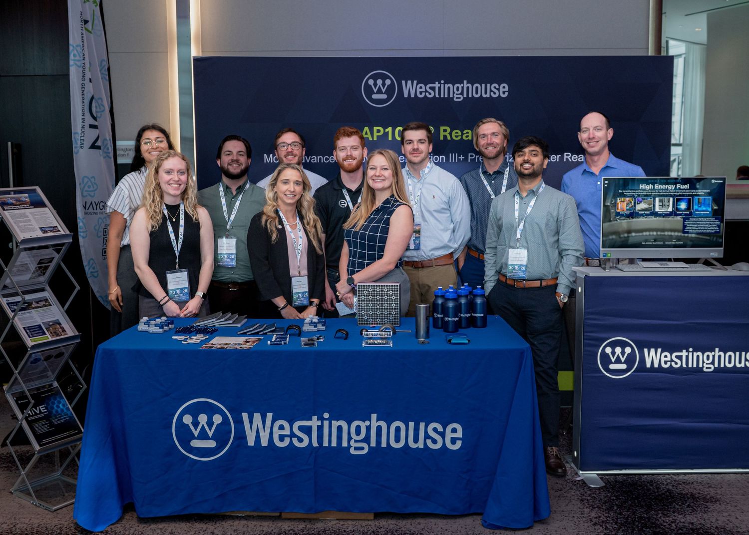 Westinghouse team members smile at a branded booth display during a professional conference or trade show event.