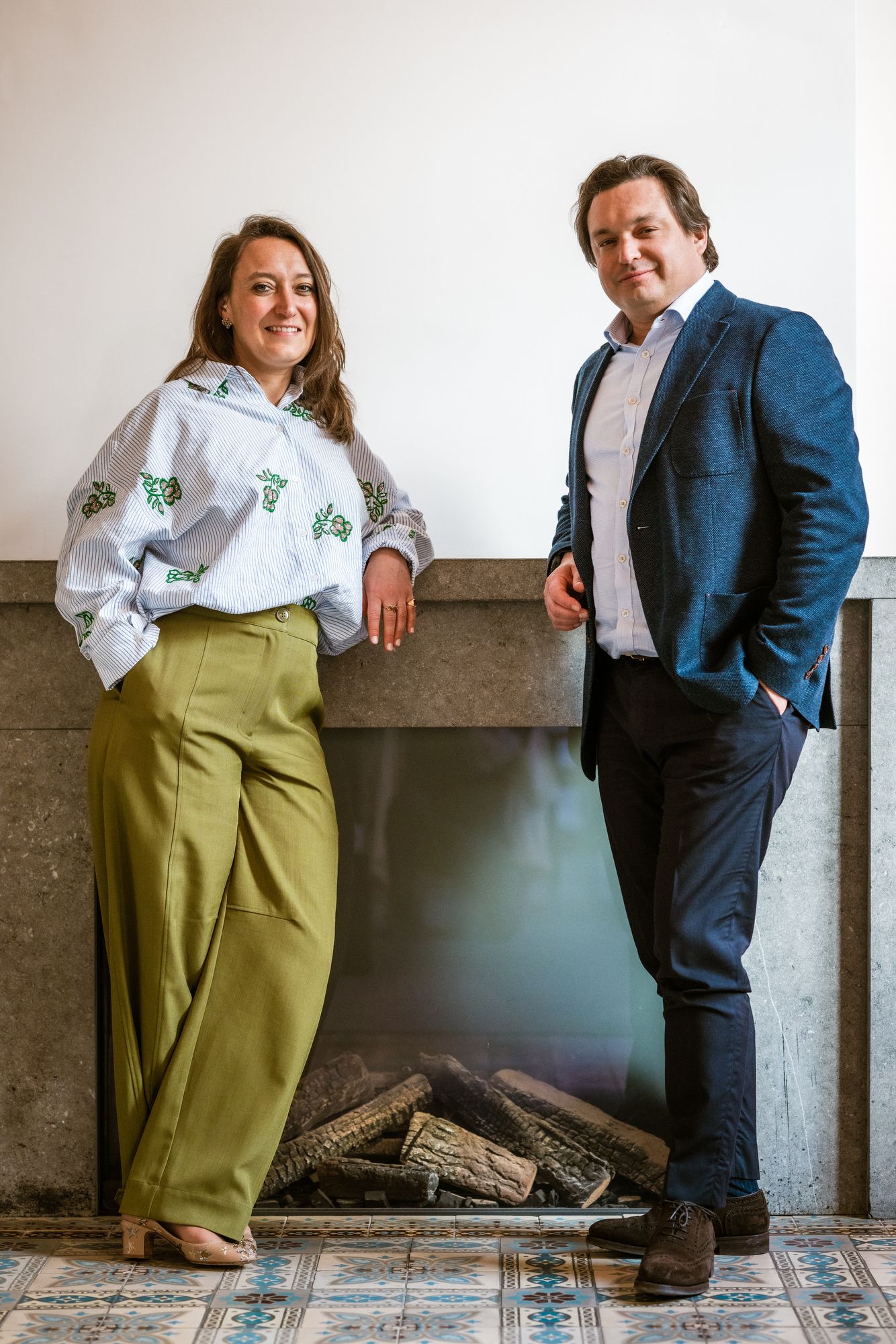 Twee ondernemers poseren professioneel bij een haard voor een B2B portret, vastgelegd door Bart Boodts Photography.