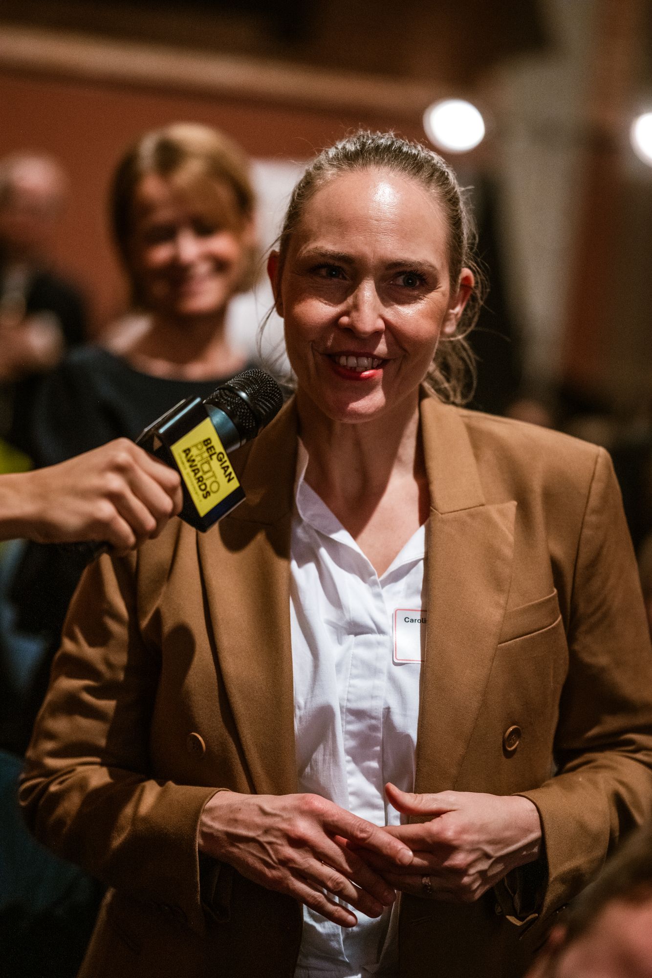 Ondernemer geeft interview met microfoon op netwerkevent, vastgelegd tijdens een B2B reportage door Bart Boodts Photography.