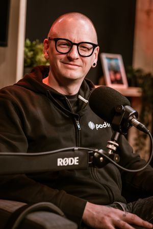 Glenn De Wilde in podcaststudio Podio tijdens podcastopname met microfoon, vastgelegd in een B2B reportage door Bart Boodts Photography.