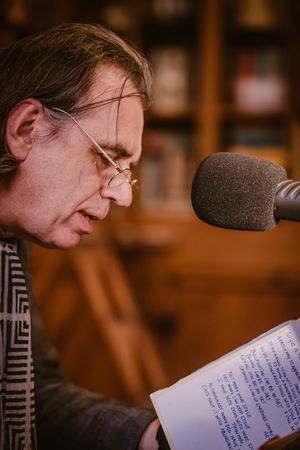 Dirk De Wachter leest voor in microfoon tijdens opname, vastgelegd in een B2B reportage door Bart Boodts Photography.