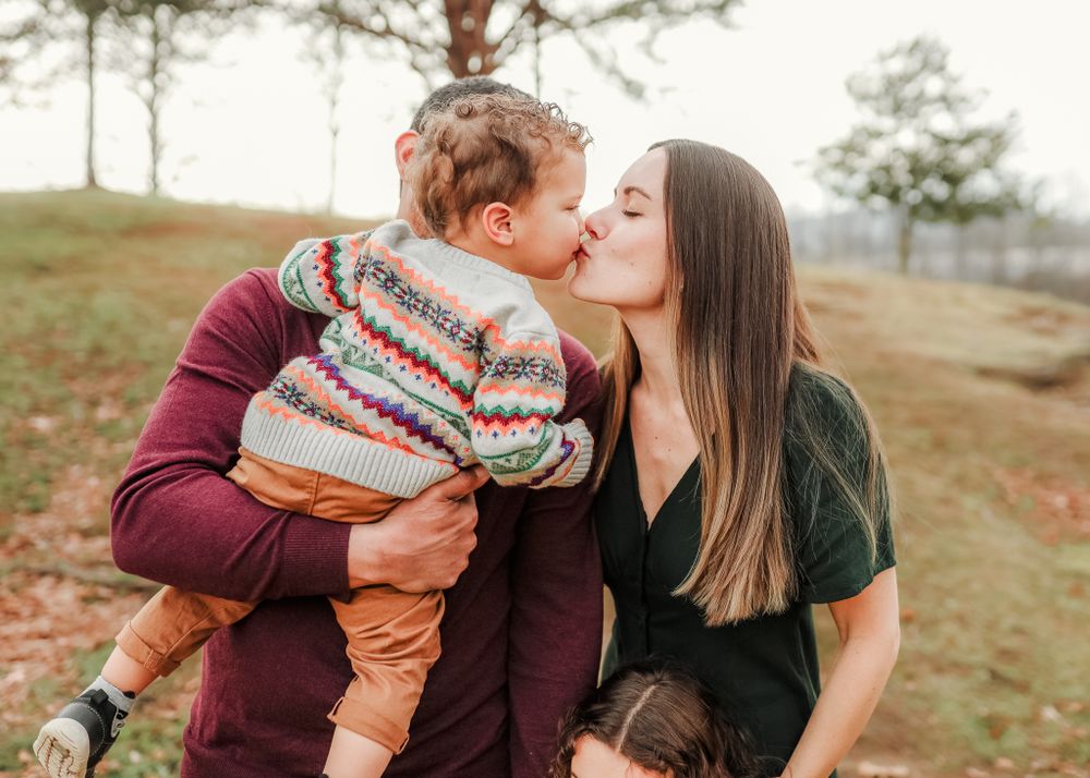 Sweet outdoor family moment in the autumn showing affection while wearing cozy sweaters in nature.