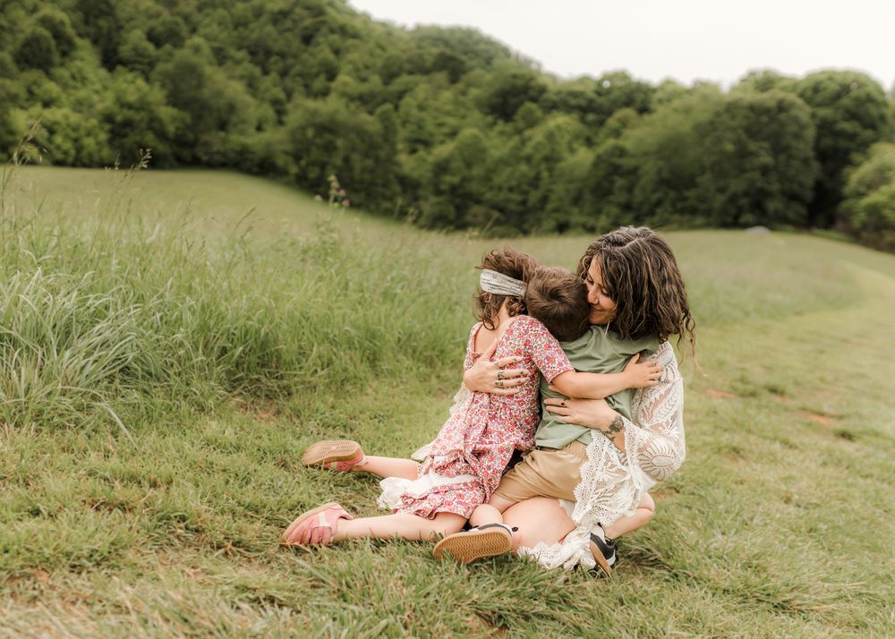 Two people lounging together on a grassy hillside in casual summer outfits on a sunny day.