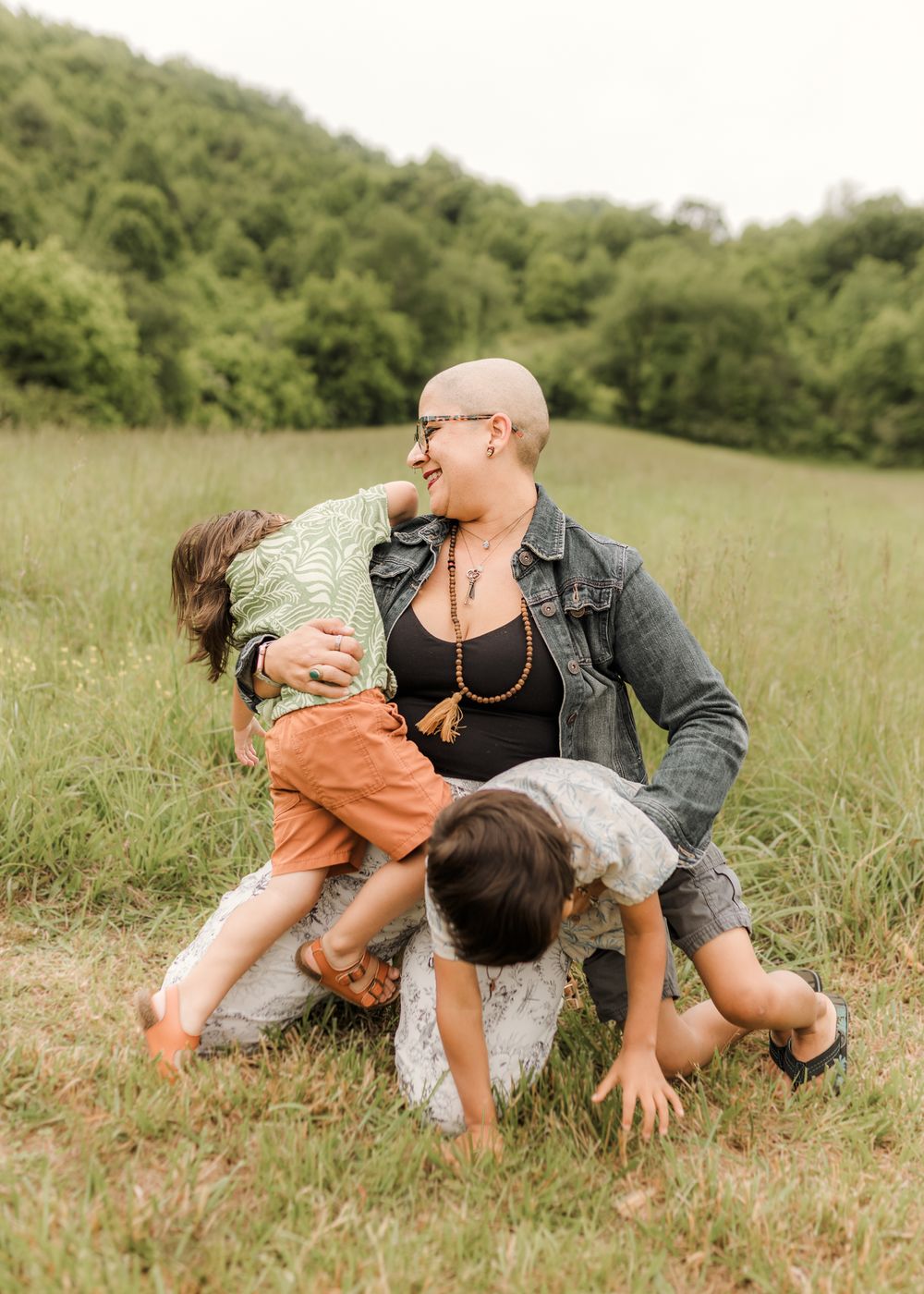 A playful sequence of people rolling and laughing together in a sunny meadow with tall grass.
