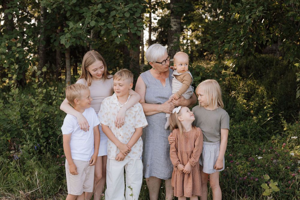 Isoäiti ja lapsenlapset yhteiskuvassa niityllä kesäillallassa. Sukukuvaus, perhekuvaus, aineeton lahja, lapsikuvaus, Tampere.