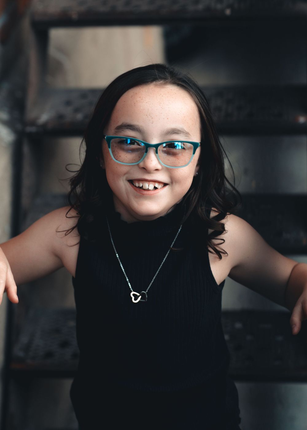 A child wearing glasses and black clothing smiles and poses in a creative photo collage sequence.