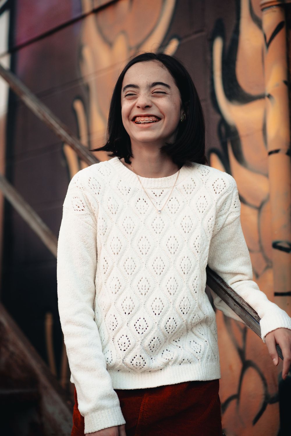 A person in a white knit sweater laughs joyfully against a dark background in a multi-panel photo sequence.