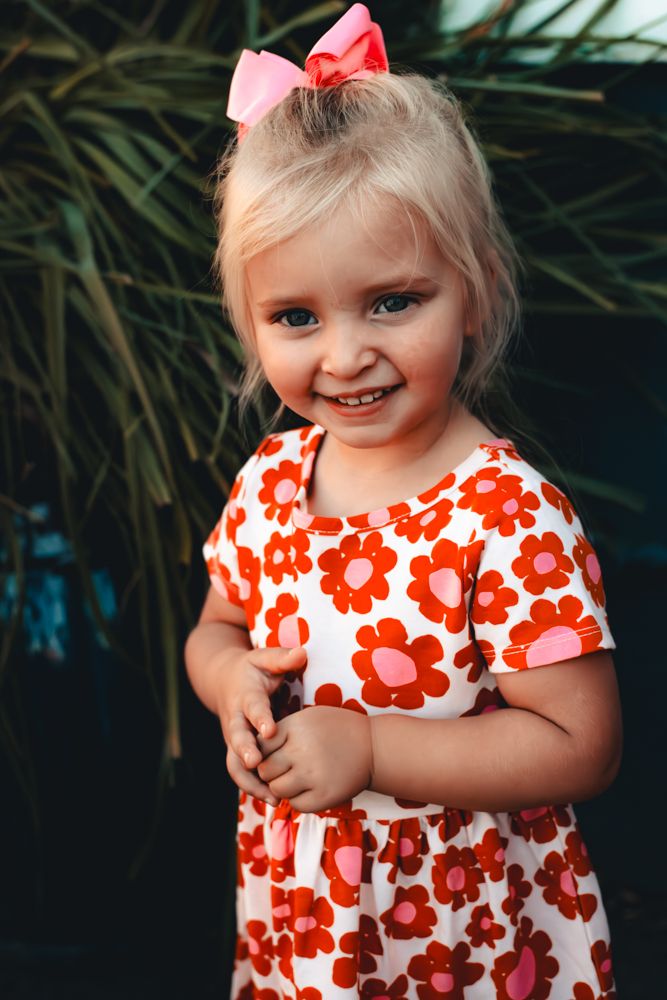 A child wearing a white and red floral print dress poses playfully in a series of connected photos.