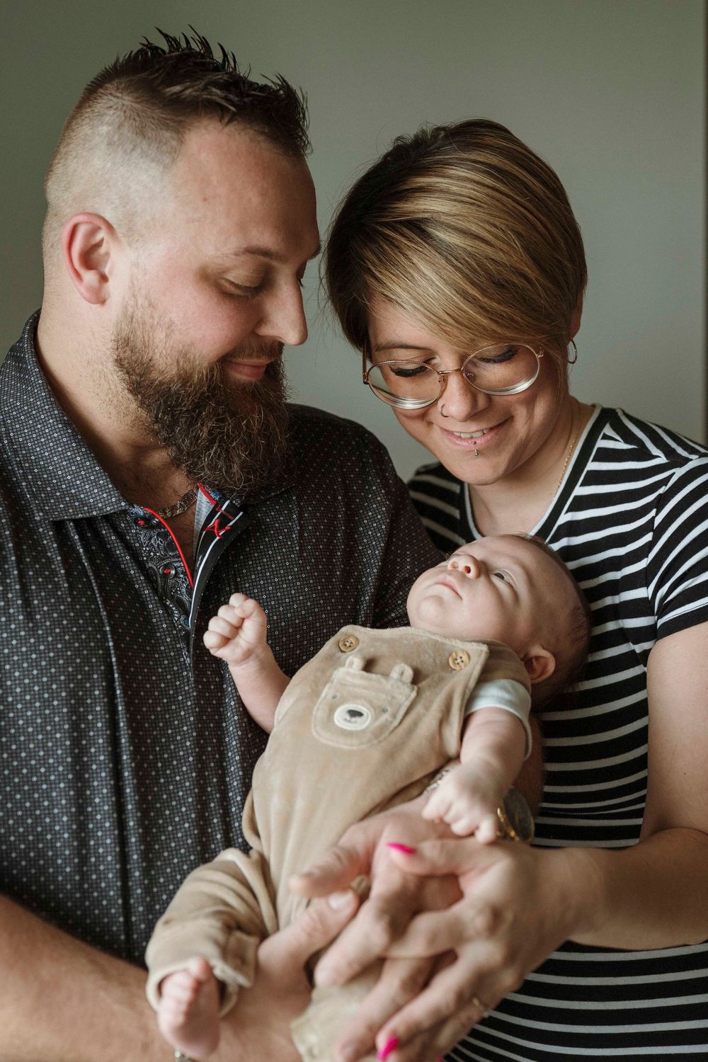 A series of intimate family moments showing parents holding and bonding with their newborn baby in black and white tones.