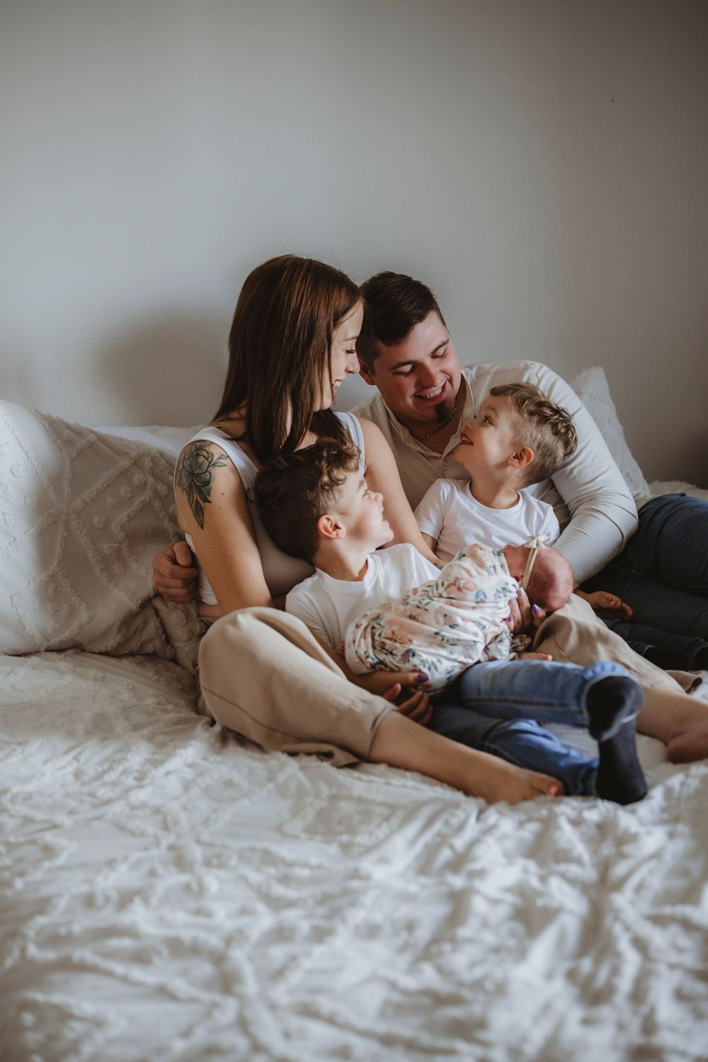 Family relaxing together on white bedding in a cozy lifestyle photoshoot.