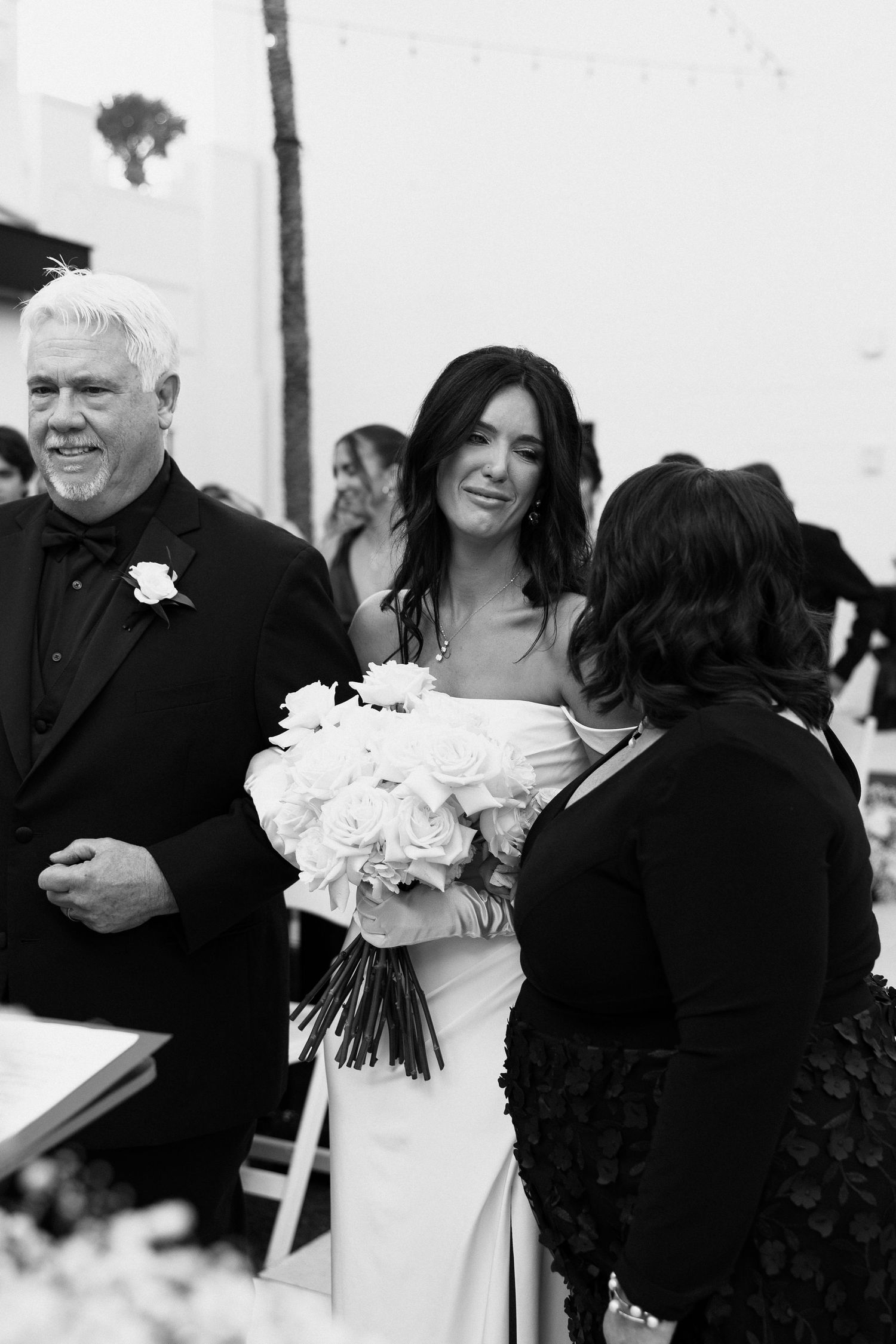 Bride emotionally looking at her mother while her mom and dad give her away.