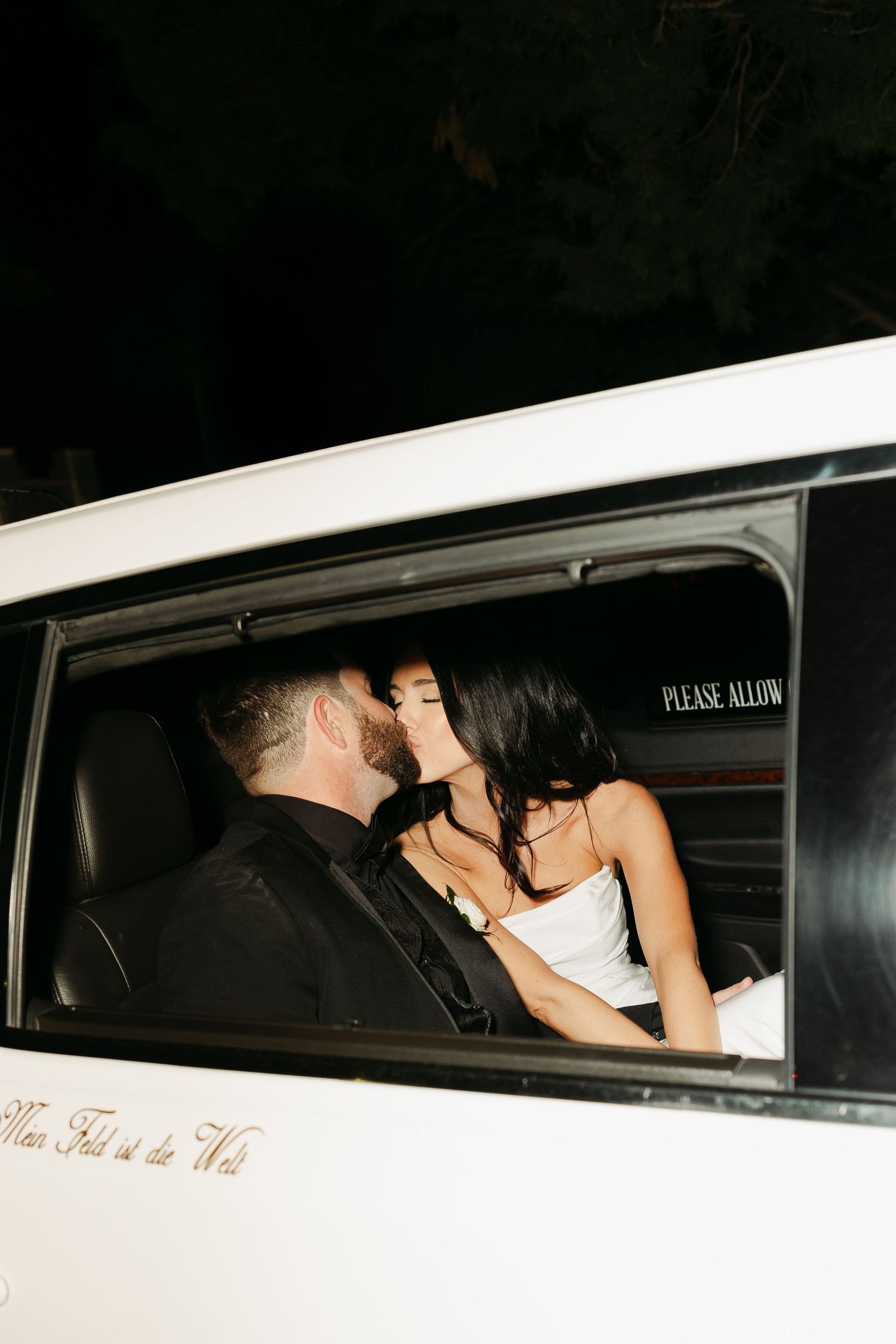 Bride and Groom lean in for a sweet kiss in a limo to end their beautiful wedding day.